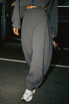 Front view of model from the waist down posing in the oversized, horseshoe-style jet nylon Barrel Pant with side pockets, zip fly, pleated sides and adjustable snap closures at the ankle.