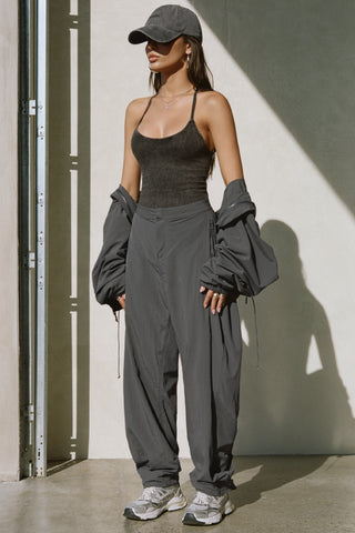 Full body front view of model posing in the oversized, horseshoe-style jet nylon Barrel Pant with side pockets, zip fly, pleated sides and adjustable snap closures at the ankle.