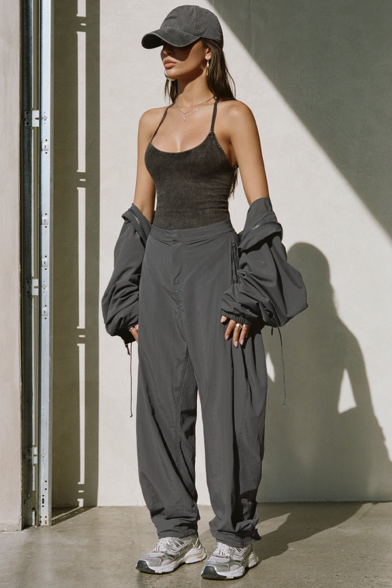 Full body front view of model posing in the relaxed-fit jet Classic Windbreaker Jacket with a padded collared neck for structure & adjustable corded details at the sweep for cinching