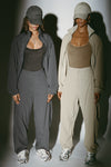 Two models posing in a jet nylon and desert sage nylon Classic Windbreaker Jacket and Barrel Pant sets