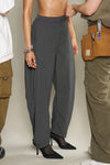 Front view of model from the waist down posing in the oversized, horseshoe-style jet nylon Barrel Pant with side pockets, zip fly, pleated sides and adjustable snap closures at the ankle.