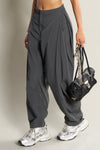 Front view of model from the waist down posing in the oversized, horseshoe-style jet nylon Barrel Pant with side pockets, zip fly, pleated sides and adjustable snap closures at the ankle.
