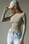 Front view of model posing in the fitted, light weight sage modal Boatneck Long Sleeve with a boat neckline