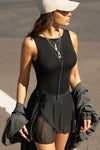 Side view of model posing outside in the street in the fitted, lightweight black modal Boatneck Tank top with a boat neckline