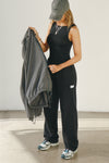 Full body side view of model posing in the fitted, lightweight black modal Boatneck Tank top with a boat neckline