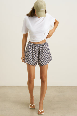 Full body front view of model posing in the relaxed fit navy dice satin Breezy Short with an elastic waistband, side pockets and a slightly curved hemline