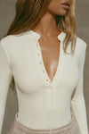 Close up front view of model posing in the fitted and stretchy bone rib Button Down Henley long sleeve top with a high crew neckline and front buttons that reach about halfway down the shirt