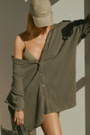 Front view of model posing in the oversized olive gauze Button Down Tunic short sleeve top with a collared neckline and dropped shoulders and a back button that can be fastened to cinch the waist for shape