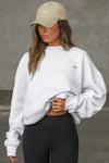 Front view of model posing in the soft oversized pearl grey french terry Classic Crew Pullover sweatshirt with a crew neckline and joah brown logo patch sewn on the upper left chest