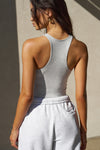Back view of model posing in the pearl grey flexrib Classic Racerback Tank with a scoop neckine and racerback silhouette. 
