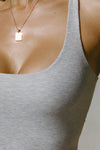 Close up detail front view of model posing in the pearl grey flexrib Classic Racerback Tank with a scoop neckine and racerback silhouette. 
