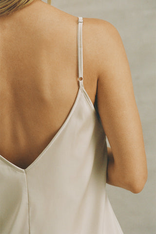Close up detail back view of model posing in the relaxed fit champagne satin Classic Slip Dress delicate adjustable straps, a v-neckline and deep v-back