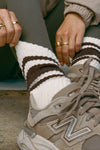 Close up detail front view of model adjusting the crew style ribbed soft tobacco Classic Stripe Sock