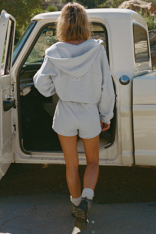 Full body back view of model posing outside next to a truck in the relaxed fit cloud french terry Classic Sweat Short with side pockets, hidden drawstring, adjustable elastic waistband and JOAH BROWN logo patch on the bottom left leg