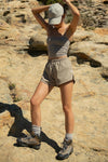 Full body front view of model posing outside in the relaxed-fit desert sage nylon Classic Track Short with an elastic waistband, side seam pockets, and adjustable drawcord
