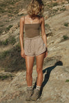Full body front view of model posing outside in the relaxed-fit fawn nylon Classic Track Short with an elastic waistband, side seam pockets, and adjustable drawcord.