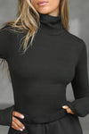 Close up front view of model posing in the form fitting stretchy vintage black rib Classic Turtleneck long sleeve top