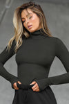 Front view of model posing in the form fitting stretchy vintage black rib Classic Turtleneck long sleeve top