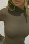 Close up detail front view of model posing in the form-fitting and stretchy woodland rib Classic Turtleneck long sleeve top