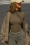 Front view of model posing outside in the street in the form-fitting and stretchy woodland rib Classic Turtleneck long sleeve top