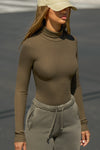 Front view of model posing outside in the street in the form-fitting and stretchy woodland rib Classic Turtleneck long sleeve top