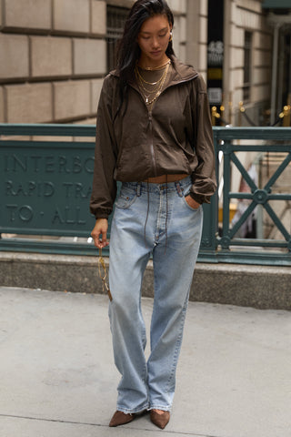 Full body front view of model posing in a city  in the relaxed-fit espresso nylon Classic Windbreaker Jacket with a padded collared neck for structure & adjustable corded details at the sweep for cinching