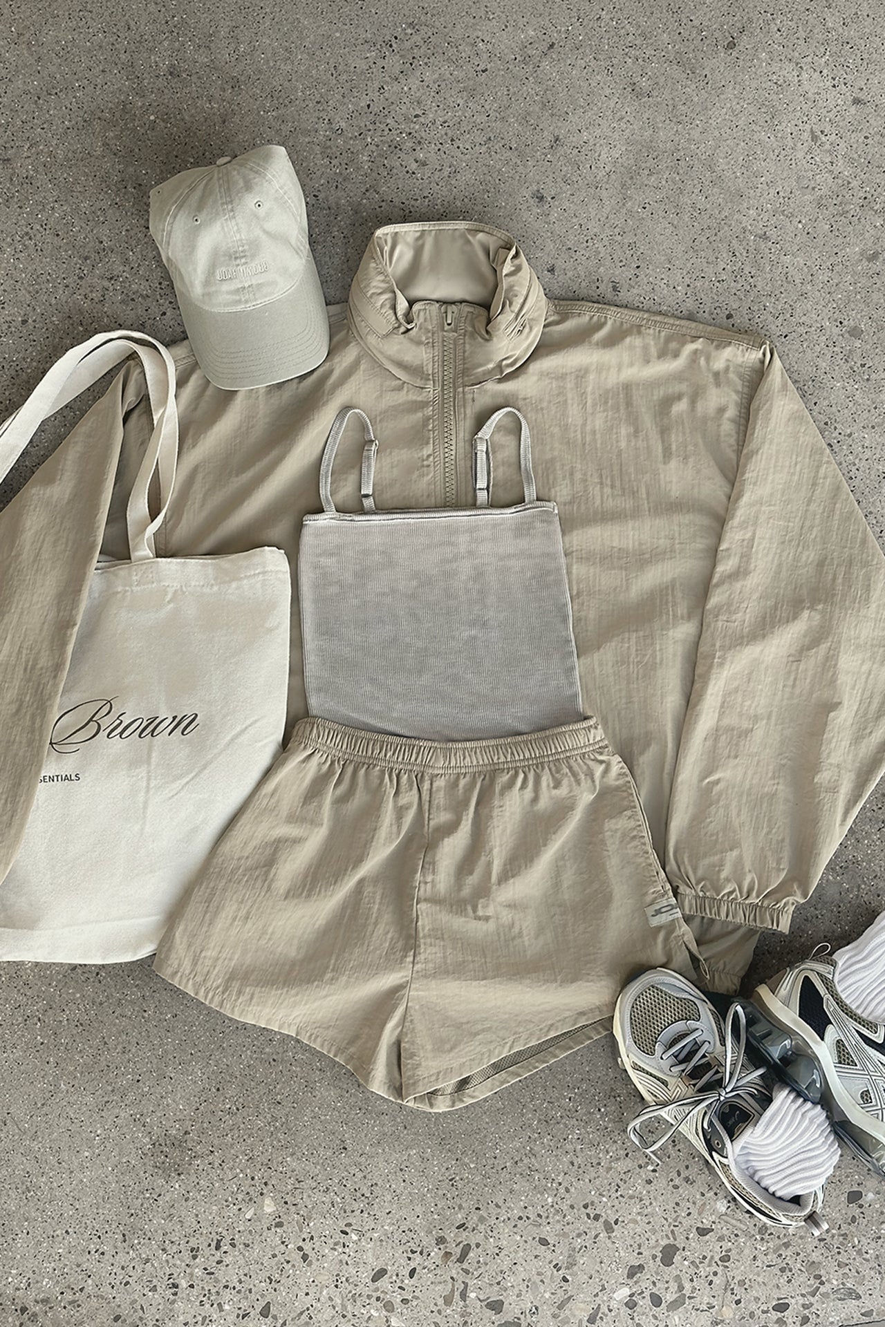 Flat lay view of the dune washed rib Square Neck Cami, desert sage nylon Classic Windbreaker Jacket, desert sage nylon Classic Track Short, sahara Official Cap and salt Scrunch Sock