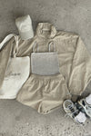 Flat lay view of the dune washed rib Square Neck Cami, desert sage nylon Classic Windbreaker Jacket, desert sage nylon Classic Track Short, sahara Official Cap and salt Scrunch Sock