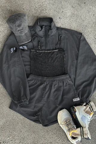 Flat lay view of the charcoal washed rib Square Neck Cami, jet nylon Classic Windbreaker Jacket, jet nylon Classic Track Short, washed black Official Cap and oat and olive Hiker Sock