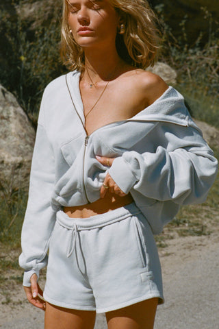 Front view of model posing outside in the relaxed fit cloud french terry Classic Zip Hoodie with a full length front zip closure, side pockets and thumbholes in the fitted cuffs
