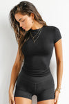 Front view of model posing in the form fitting black rib Crewneck Tee with a banded crew neckline and banding at the sleeves