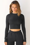 Front view of model posing in the fitted cropped black rib Cropped Crew Long Sleeve top with a crew neckline