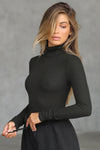 Side view of model posing in the form fitting stretchy vintage black rib Classic Turtleneck long sleeve top