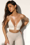 Front view of model posing in the fitted natural luxe knit Cropped Triangle Cami with triangle cup seaming along the bust, thin corded straps and a front center opening banded together with delicate knot buttons
