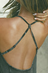 Close up detail back view of model posing in the fitted charcoal washed rib Cross Back Cami with a scoop neckline and thin adjustable straps that criss cross in the back