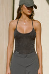 Front view of model posing in the fitted charcoal washed rib Cross Back Cami with a scoop neckline and thin adjustable straps that criss cross in the back