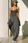 Full body front view of model posing in the fitted charcoal washed rib Cross Back Cami with a scoop neckline and thin adjustable straps that criss cross in the back