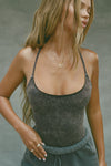 Front view of model posing in the fitted charcoal washed rib Cross Back Cami with a scoop neckline and thin adjustable straps that criss cross in the back