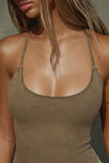 Close up detail front view of model posing in the fitted sepia washed rib Cross Back Cami with a scoop neckline and thin adjustable straps that criss cross in the back