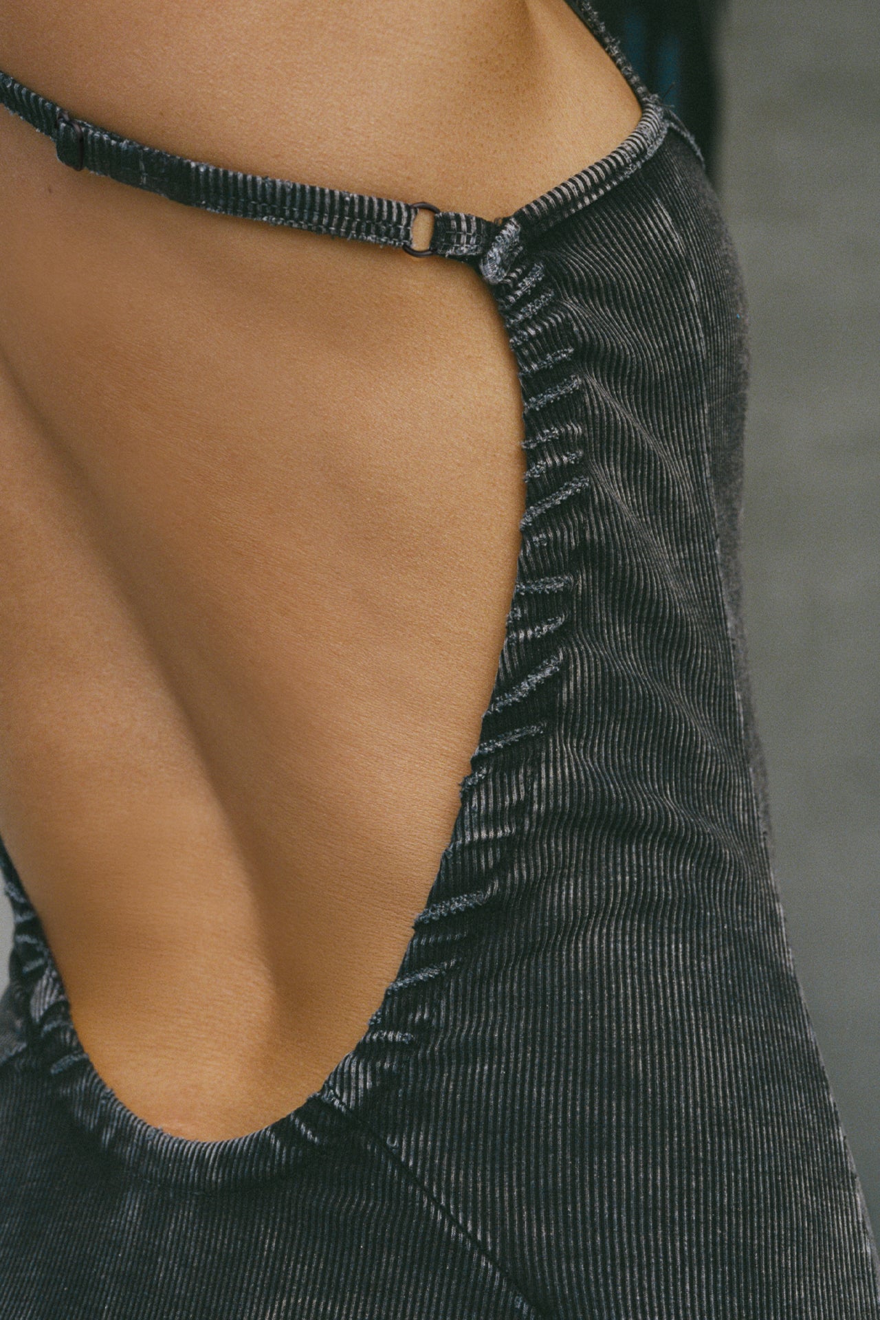 Close up detail back view of model posing in the fitted  charcoal washed rib Cross Back Midi Dress with an asymmetrical hem, a low scoop back and thin adjustable straps that criss cross in the back