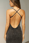 Back view of model posing in the fitted  charcoal washed rib Cross Back Midi Dress with an asymmetrical hem, a low scoop back and thin adjustable straps that criss cross in the back