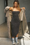 Full body front view of model posing in the fitted  charcoal washed rib Cross Back Midi Dress with an asymmetrical hem, a low scoop back and thin adjustable straps that criss cross in the back