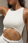 Close up front view of model posing in the fitted cropped bone flexrib Curve Crop Tank wih a vertical stitch detail down the front, a curved hemline in an inverted u-shape and a high v-neckline