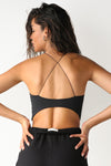Back view of model posing in the ultra-cropped sueded onyx Curve Scrunch Tank with delicate corded straps in a cross back design