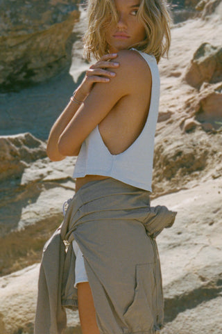 Side view of model posing outside in the relaxed fit cloud cotton Cut Off Boyfriend Tank with low cut armholes, a crew neckline and a joah brown logo patch at the upper left chest