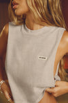 Close up front view of model posing in the relaxed fit sandstone cotton Cut Off Boyfriend Tank with low cut armholes, a crew neckline and a joah brown logo patch at the upper left chest