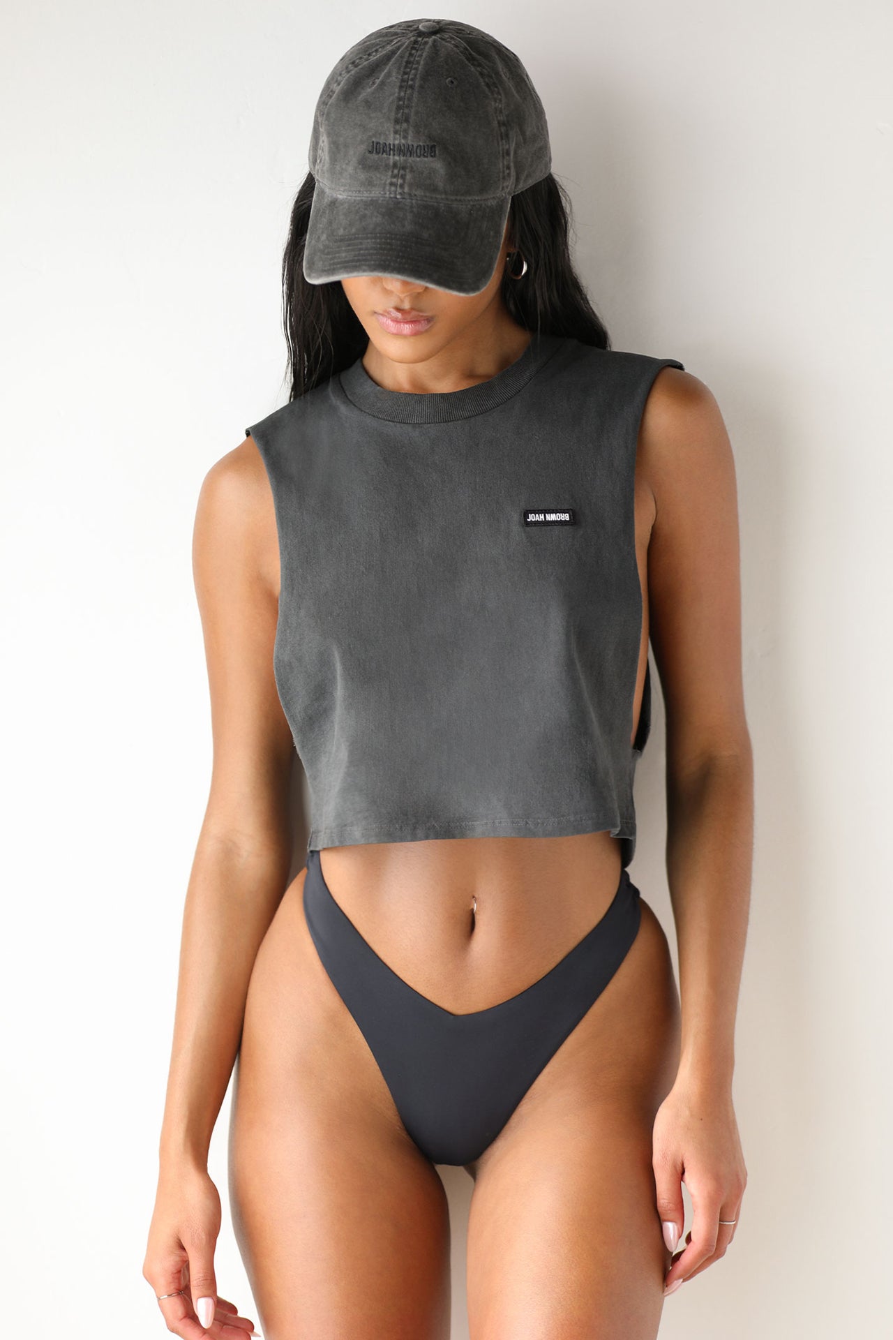 Front view of model posing in the relaxed fit washed black cotton Cut Off Boyfriend Tank with low cut armholes, a crew neckline and a joah brown logo patch at the upper left chest
