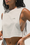 Front view of model posing in the relaxed fit fog cotton Cut Off Boyfriend Tank with low cut armholes, a crew neckline and a joah brown logo patch at the upper left chest