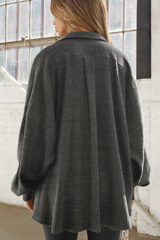 Back view of model posing in the oversized ink luxe knit Deep V Pullover with a plunging collared neckline, dropped shoulders and back panel details