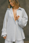 Front view of model posing in the oversized pearl grey luxe knit Deep V Pullover with a plunging collared neckline and dropped shoulders